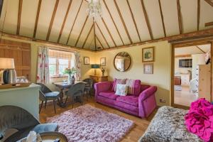 a living room with a purple couch and a table at Pond Cottage by Keepers Cottages in Egerton