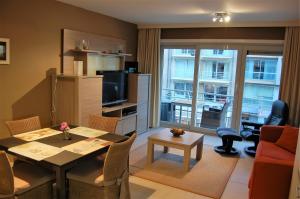 a living room with a dining room table and a living room with a view at Residentie Hof van Vlaanderen in Nieuwpoort