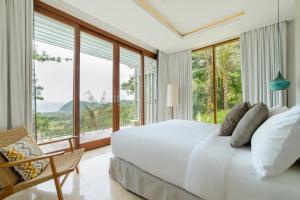 a bedroom with a large white bed and large windows at Selong Selo Resort and Residences in Selong Belanak +37 photos