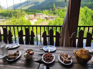 un tavolo in legno con piatti di cibo e vista di Ushba House a Mestia
