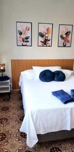 a bedroom with a white bed with four pictures on the wall at kit net em edifício no centro in São Lourenço +15 photos