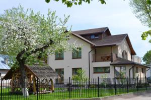 a house with a tree in front of a fence at Žemyna Apartmentai in Druskininkai