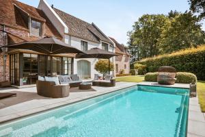 a swimming pool in front of a house at B&B Interludium in Nijlen