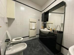 a bathroom with two sinks and a toilet and a mirror at 11 ospiti -Balcone-Parcheggio Privato, Bulai Home in Sanremo +12 photos