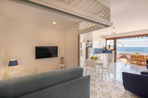 a living room with a couch and a kitchen with the ocean at Appartamento Fronte Mare con Accesso Spiaggia in Massa Lubrense