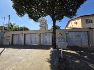 a tree in front of a building with a garage at Suíte3 Privativa Climatizada Mobiliada com Garagem e Wi-Fi in Goiânia