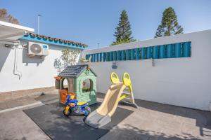 une cour avec une aire de jeux avec un toboggan et une maison dans l'établissement Melkart loft Sancti Petri, à Chiclana de la Frontera