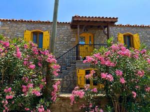 a stone house with yellow doors and pink flowers at Ilios Guest House in Gokceada Town