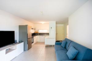 a living room with a blue couch and a kitchen at Charmant T2 à Capbreton au calme in Capbreton