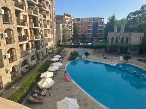 a swimming pool with umbrellas and chairs next to buildings at Kalia A7 Sunny Beach in Bŭnzareto