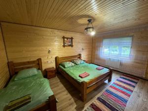 a bedroom with two beds in a log cabin at Садиба у Софійки in Synevyrsʼka Polyana