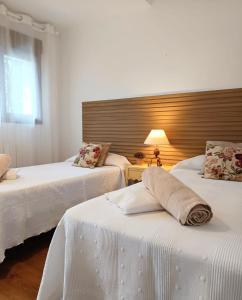a bedroom with two beds with white sheets and a lamp at Casa Rural El Olivo in Aracena