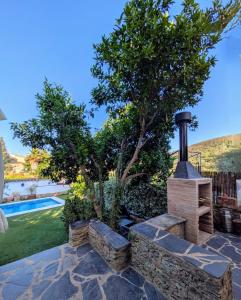 a backyard with a stone fireplace and a tree at Casa Rural El Olivo in Aracena