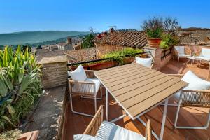 une table et des chaises en bois sur un balcon dans l'établissement Suite Scacco Terrazza Vista Torre degli Sciri, à Pérouse