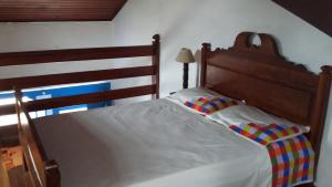 a bed with a wooden headboard and striped pillows at Casa Centro Historico in Paraty