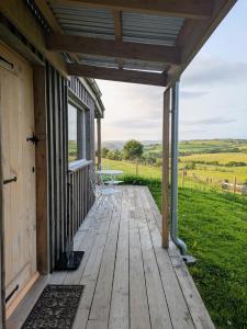 a wooden porch on a house with a view of a field at The Fold - Unique Cabin Nestled in Nature in Llangernyw