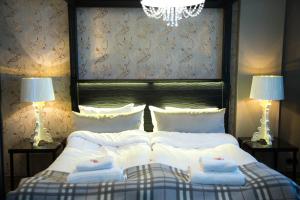 um quarto com uma cama com lençóis brancos e 2 candeeiros em Hotelli Olof em Tornio