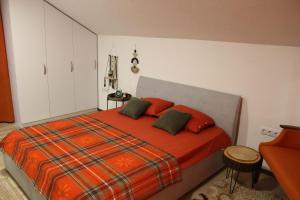 a bedroom with a bed with orange sheets and green pillows at House Trebević ReStart in Petruše