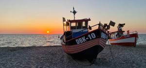two boats sitting on the beach at sunset at 365PAM - Urocze Domki Letniskowe blisko morza in Bobolin