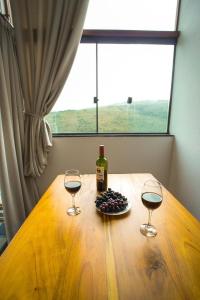 a table with two wine glasses and a bottle of wine at Chalé Por do Sol in Ouro Preto +12 photos