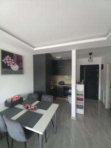 Una cocina y una sala de estar con una mesa y sillas blancas. en Apartman Jana 2, en Doboj