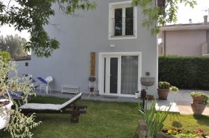 una casa blanca con un patio con una tumbona en La Capannina, en Capannori