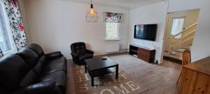 Una sala de estar con un sofá de cuero negro y un televisor. en Omakotitalo Karhula, en Kotka