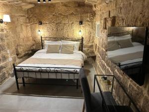 a bedroom with two beds in a stone wall at Kappella boutique in Malta in Żurrieq