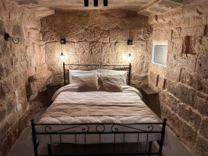 a bedroom with a bed in a stone wall at Kappella boutique in Malta in Żurrieq