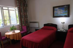 een slaapkamer met een bed, een tafel en een raam bij Hotel HAXHIU in Tirana