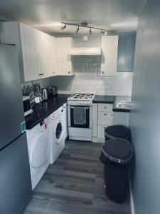 a kitchen with white cabinets and a washer and dryer at Modern Oxford Retreat - Free parking in Oxford