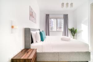 a white bedroom with a large bed and a wooden table at Stella Stays Barsha Heights in Dubai +77 photos