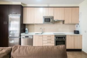 a kitchen with wooden cabinets and stainless steel appliances at Apto Llanes Piscina y Playa – El Recreo de Celorio in Celorio