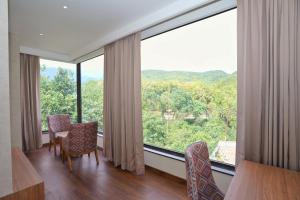 a room with a large window with chairs and a table at Hotel Malsi Mist in Dehradun