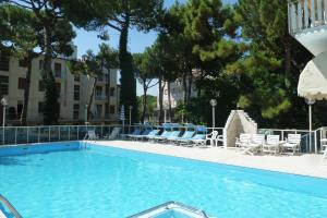 a large swimming pool with chairs and a building at Hotel Astra in Milano Marittima