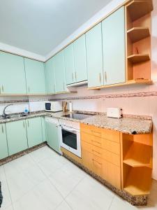 eine Küche mit grünen und rosa Schränken und Geräten in der Unterkunft Bonito apartamento en la villa marinera de Portonovo in Sanxenxo