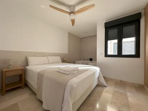 a bedroom with a white bed with a ceiling fan at Bellver Home Apartamentos in Chella +29 photos
