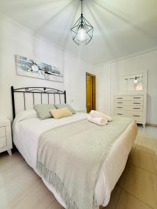 ein weißes Schlafzimmer mit einem großen Bett und einem Kronleuchter in der Unterkunft Bonito apartamento en la villa marinera de Portonovo in Sanxenxo