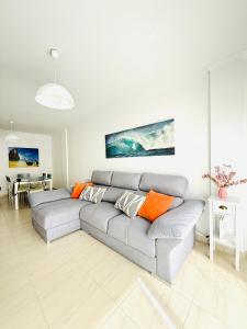 ein Wohnzimmer mit einem grauen Sofa und orangefarbenen Kissen in der Unterkunft Bonito apartamento en la villa marinera de Portonovo in Sanxenxo