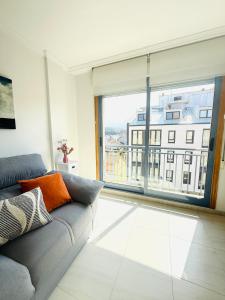 ein Wohnzimmer mit Couch und großem Fenster in der Unterkunft Bonito apartamento en la villa marinera de Portonovo in Sanxenxo