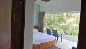 a bedroom with a bed and a balcony with a view at Bhanus Beach Enclave in Kannur