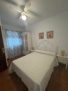a bedroom with a white bed and a ceiling fan at Casa Victoria in Conil de la Frontera