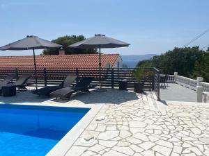 a swimming pool with chairs and umbrellas on a roof at Apartment EMMA in Povile
