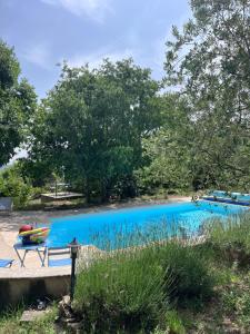 a blue swimming pool with a bench and a boat at Villa à Salazac - Piscine - Gorge de l'Ardèche in Salazac