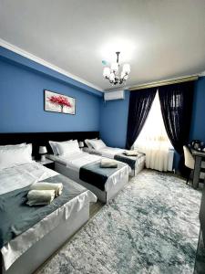 a bedroom with three beds and a blue wall at RUDAKIY Hotel in Samarkand