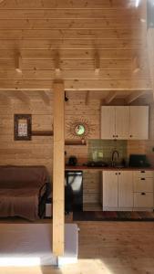 a kitchen in a log cabin with a bed and a counter at Zagroda Zabłocie Domek Komfort in Zabłocie