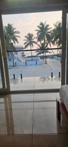 a bedroom with a view of a beach and palm trees at Bhanus Beach Enclave in Kannur