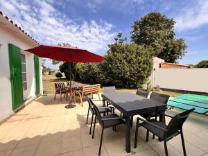 a patio with a table and chairs and a red umbrella at OPALINE maison spacieuse proche plage in Sainte-Marie-de-Ré