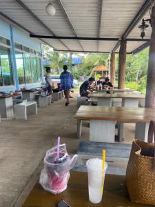 a restaurant with tables and people sitting at tables at Riverside Pak Nakon Restaurant & hostel in Ban Ko Mai Phai
