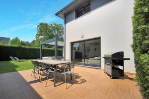 un patio con griglia, tavolo e sedie di La Villa Sainghin - Piscine et Jacuzzi Privé a Sainghin-en-Mélantois